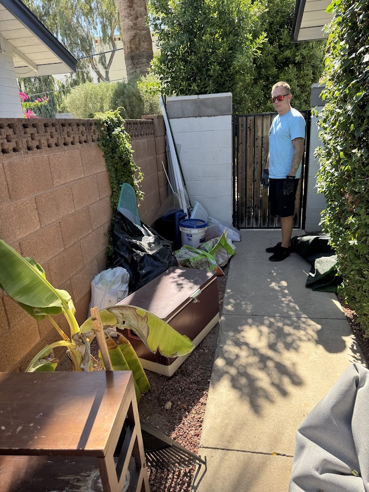 Cluttered side yard with construction debris and materials before removal